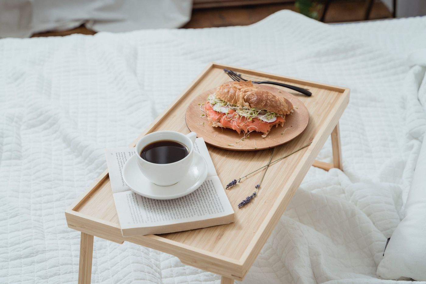 Plateau de petit déjeuner avec café posé sur un lit